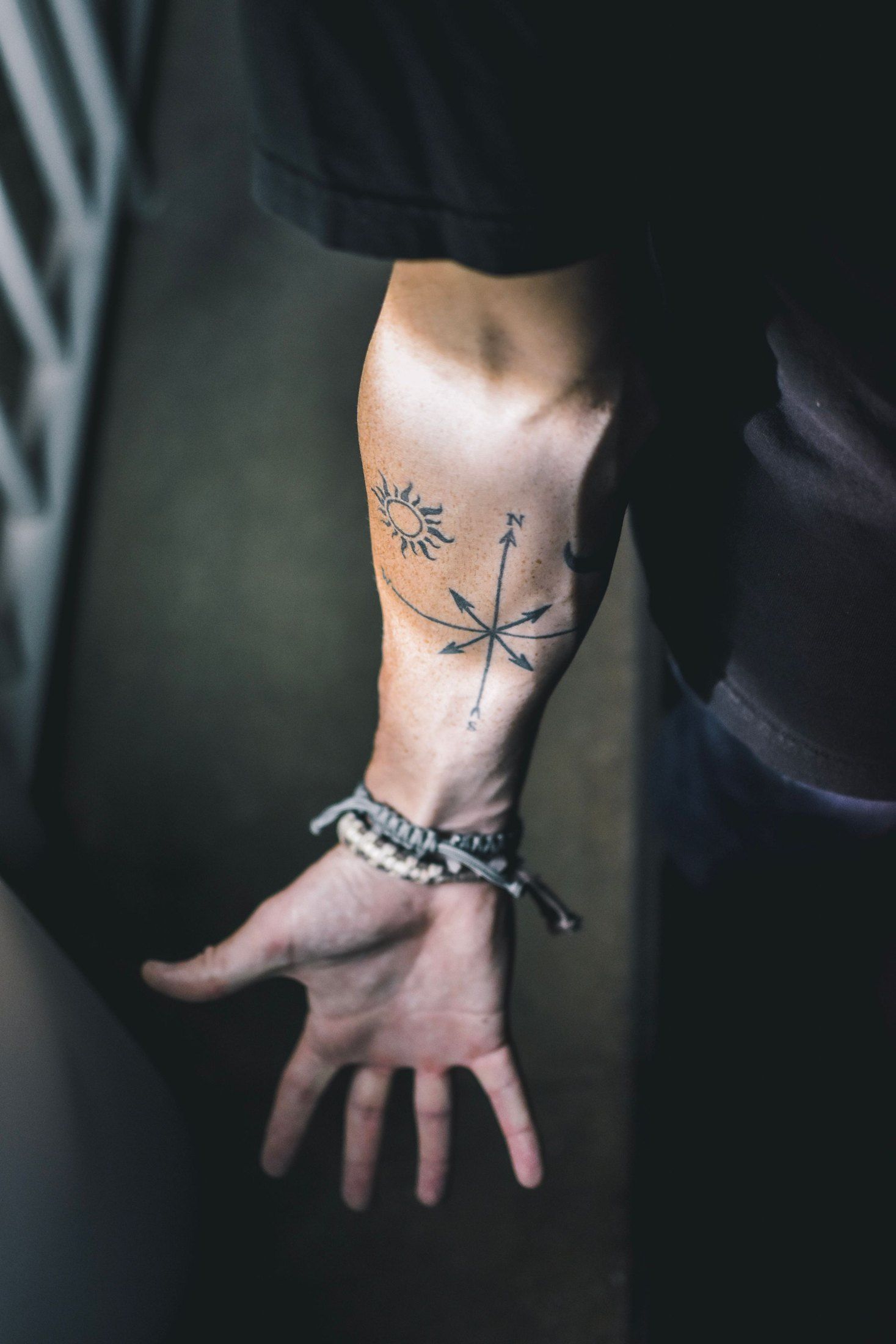 Unterarm mit einem Kreuz aus feinen Pfeilen und einer kleinen Sonne, die Hand geöffnet