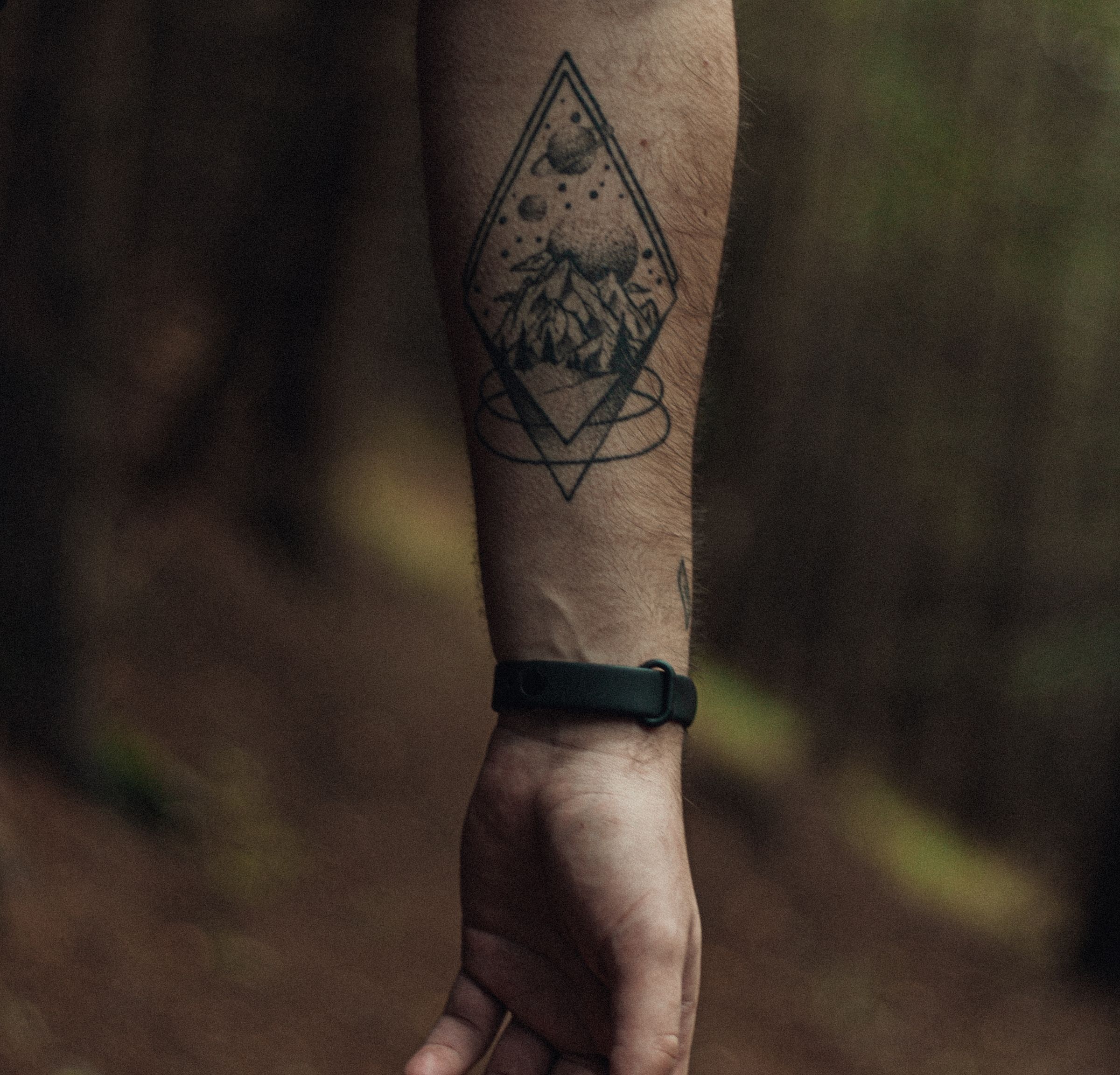 Unterarm mit einer Raute aus geraden Linien, darin eine Landschaft aus Punkten